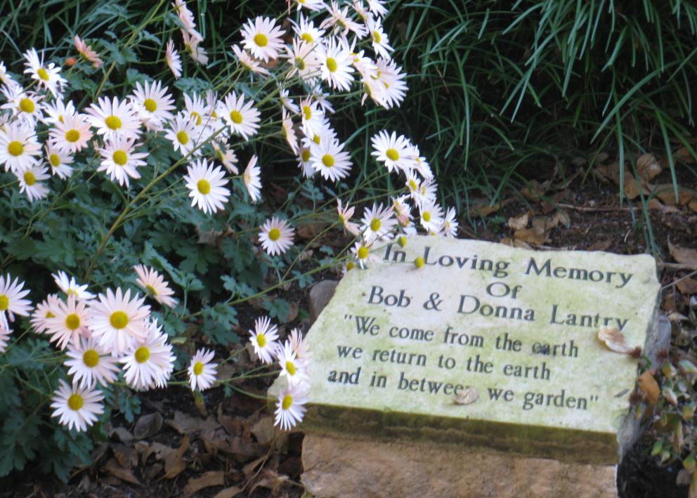 memorial stone that says "In Loving Memory of Bob & Donna Lantry - we come from the earth, we return to the earth, and in between we garden"