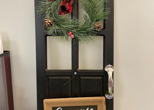 Door number two, which is Colin's door. Colin is our front desk worker, and he doesn't have an office door, so this is actually a minituare door and it sits on his desk top! It has a sign that says "Season's Greeetings" and an evergreen reef. 