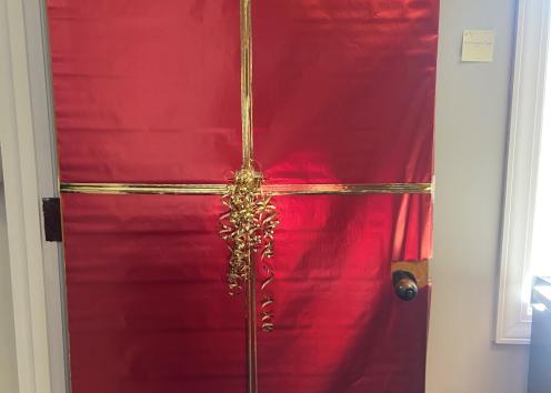 This door, door number three, is decorated like a giant Christmas present. Its wrapped in shiney red wrapping paper and a golden bow.