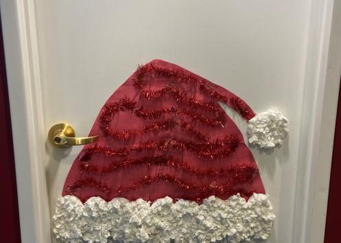 Door number six features a large Santa hat made from red paper and red garland and white tissue paper. 